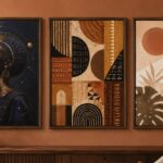 Three wall art pieces side by side on a clay-toned wall — a cosmic Afrofuturist portrait in bronze, an Afrocentric textile-pattern abstract in earth tones, and a soft Afro-bohemian botanical in cream and terracotta, afrofuturism vs afrocentric