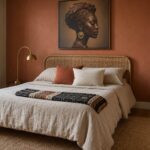 Afro-boho bedroom with rattan headboard, mudcloth throw, framed Black portrait, brass lamp, warm terracotta accent wall