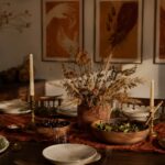 Black Thanksgiving decor: a rust and clay harvest table with dried grains and Afrocentric gratitude wall art behind