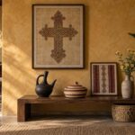 Ethiopian symbols in a styled room — framed interlaced Ethiopian cross print, woven tilet panel and black clay jebena